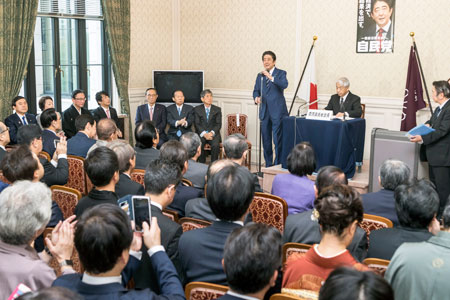 自民党両院議員総会で挨拶する安倍総裁(奥に立っている人)